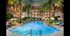 A landscaped courtyard with a large pool, lounge chairs, cabanas, and palm trees.