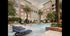 A landscaped courtyard with a large pool, in-pool lounge chairs, cabanas, and palm trees.