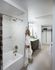 Spacious bathroom with an attached walk-in closet, tile floors, and a large bathtub with marble tile walls