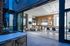 An indoor lounge with social seating, bar areas, and a wall of retractable floor-to-ceiling glass doors that open to the outdoor rooftop lounge.
