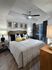 Bedroom with wood-style floors, large window, recessed ceiling with a fan, king-sized bed, two nightstands, and a dresser