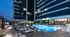 Outdoor pool deck with lounge chairs surrounding the pool and in the shallow end, two cabanas, and apartment homes overlooking the deck.