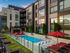 Elevated outdoor pool deck with landscaping and upholstered lounge chairs.