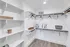 walk-in closet with white wooden shelving and hanging racks