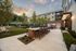 courtyard with two grills and two dining tables next to a green lawn space with lounge chairs