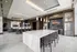 large clubroom with kitchen with waterfall granite counters and 8 counter chairs and stainless steel french door fridge and more seating areas in the background