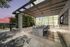 elevated covered deck with 6-seater stone dining table, landscaping, and tv over looking the houston skyline at sunset
