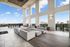 two story outdoor covered terrace with 10-top bar height outdoor dining table and 3 groups of 2 chairs with small table and two large corner sectional sofas, with view of downtown Houston