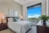 apartment bedroom with king size bed and two night stands and dresser, oversized picture window showing sweeping Houston views
