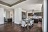 Kitchen and dining area with wet bar with wine fridge, 6-seater dining table, and a kitchen with floating vent hood and spacious kitchen island and brown tone cabinets