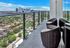 balcony on the 30th floor with patio conversational seating area, glass railing and views of downtown Houston in the background