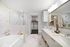 bathroom with white marble tiling and white wood cabinetry, featuring soaking tub, glass shower and double vanity