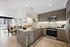 u-shaped kitchen in an apartment with brown-tone wood cabinetry, neutral stone counters, and stainless steel appliances