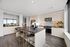apartment kitchen with center island, built-in dry bar with mirror, light white wood cabinets, black stone counters, and brown wood-style flooring.