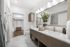 bathroom with white marble tile floors and double vanity with framed mirror, with closet attached