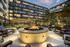 firepit in apartment courtyard surrounded with outdoor chairs, with string lights and lawn space behind