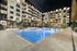 pool in courtyard of apartment building with in water chairs and two rows of sun-loungers next to the pool