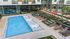 birdseye view of apartment pool with tanning ledge and chairs and two rows of sun loungers next to the pool