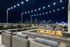 sky deck with string lights, low stone fireplace, lounge seating, and bar ledge with stools over looking downtown Denver at night