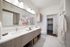 vanity of bathroom with two sinks, framed mirror, toilet and closet attached