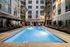 pool of apartment community lit up at night with cushioned lounge chairs and cabanas