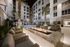 courtyard of 6-story apartment building with rectangular open fire pit surrounded by 6 cushioned chairs