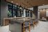 entertaining kitchen with island with 5 counter stools and adjacent counter with sink and sliding windows behind