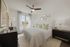 bedroom in apartment with king size bed, oversized windows, and ceiling fan light fixture
