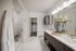 bathroom with dual vanity, framed mirror, glass frameless shower, white marble tile, and door to closet