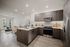 apartment with u-shaped kitchen with brown cabinets, white counters and stainless steel appliances and living space beyond