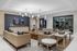 Elegant modern living room with luxurious beige leather sofas, a wooden coffee table, and contemporary lighting fixtures creating a sophisticated ambiance.