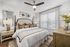 Cozy and elegant bedroom featuring a plush king-sized bed, stylish decor, and abundant natural light through large windows.