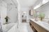 Luxurious modern bathroom featuring marble tile, dual sinks, elegant decor, and a spacious walk-in closet.