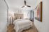 Elegantly designed bright bedroom featuring a cozy bed, modern artwork, and stylish lighting, with hardwood flooring.
