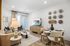 Modern living and dining area featuring elegant decor, a cozy beige sofa, stylish lamp, tasteful wall art, and a large flat-screen TV.