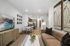 Modern living room featuring an elegant sofa, artistic decor, and a contemporary dining area, leading to a sleek open kitchen.