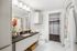 Elegant modern bathroom with sleek countertop, stylish fixtures, and a spacious walk-in closet.