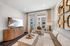 Bright and chic living room with stylish decor, featuring a cozy sofa, modern art pieces, and large windows offering natural light.