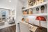 Bright and modern apartment living room with elegant decor and a cozy workspace. Features chic shelving, stylish lighting, and a comfortable seating area with natural light from large windows.