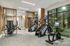 Contemporary fitness center with state-of-the-art exercise equipment, sleek wood finishes, and large windows providing natural light.