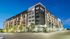 Elegant multi-story apartment building with modern architecture, illuminated against a twilight sky, surrounded by lush landscaping.