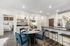 Modern open-concept kitchen and dining area with stylish decor, featuring a cozy table setting for four and sleek bar stools under granite countertop.