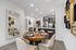 Contemporary dining and kitchen area with elegant decor, featuring a wooden round table set for four and a modern kitchen with stainless steel appliances.
