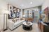 Contemporary living room with a cozy white sofa, abstract art, and large windows offering a view of urban architecture.