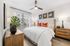 Chic bedroom with contemporary decor, featuring a plush bed, modern ceiling fan, stylish wooden furniture, and vibrant red accents.