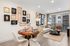 Modern living and dining area with elegant wall art, featuring a cozy round table set for four, plush cream chairs, and an inviting sofa with stylish decor in a bright, well-lit space.