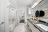 Elegant bathroom with marble tiles, stylish vanity, and walk-in closet access offering modern luxury.