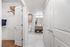 Modern apartment bathroom with elegant vanity, stylish cabinet, and spacious walk-in closet featuring wooden flooring.