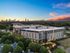 Chic urban apartment complex with modern design, surrounded by lush greenery and offering stunning sunset views of the city skyline.