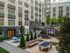 Modern apartment courtyard featuring lush greenery, outdoor seating, and recreational areas with a sleek urban design.